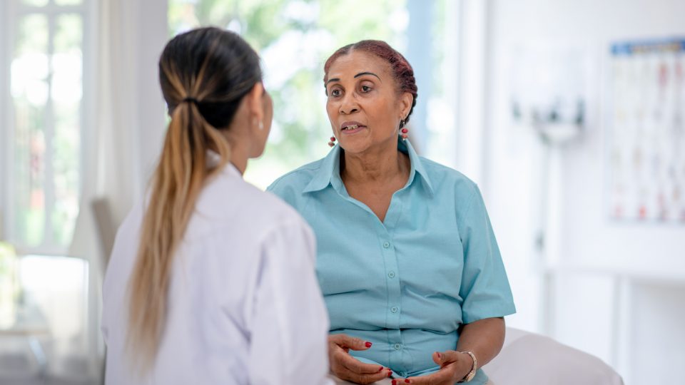 Older patient speaking with healthcare provider in exam room