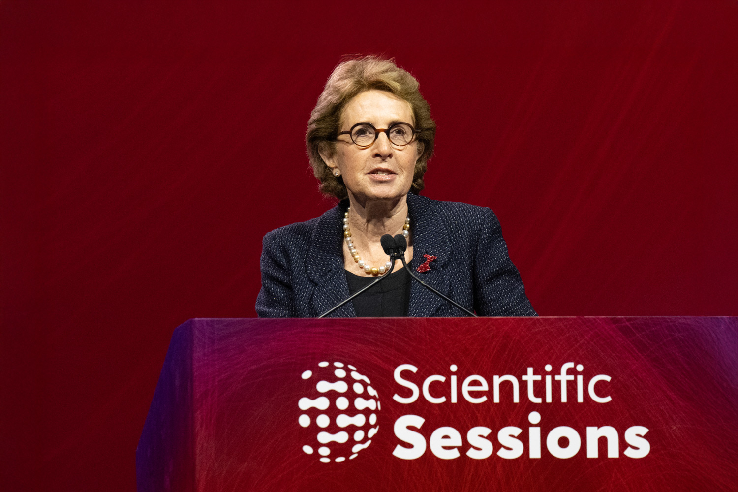 Dr. Judith Hochman speaks behind a podium that says Scientific Sessions